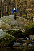 Trial biker on rock at river, Muehlviertel