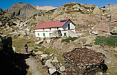 Certascan lodge, Certascan peak on the back with hiker. Pallars Sobirà. Lleida province. Catalunya. Pyrenees Mountains. Spain
