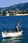 Fisherman on boat in front of Korcula Island. Croatia