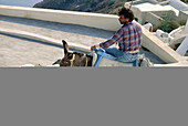 Man climbing stairs on his donkey back at village. Santorini island. Greece