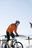 Mann fährt Mountainbike im Schnee, Steiermark, Österreich