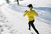 Frau joggt über verschneiten Weg, Steiermark, Österreich