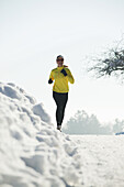 Woman jogging on snowy road, Styria, Austria