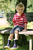 Boy (4-5 years) sitting on a bench, Styria, Austria