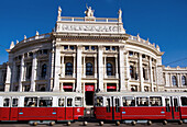 Austria, Vienna. Hofburg theatre with red trams