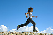 Girl running along seaside kicking