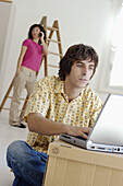 Couple moving home, the boy with laptop while the girl with mobile phone