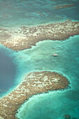 Aerial view of Blue Hole, sailboat anchored nearby, Lighthouse Atoll, Belize