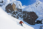 Heliskiing Kamtschatka, Sibirien, Russland, ein Mann fährt im Tiefschnee vor Felskulisse vom Viljuchinsky Vulkan, 2173m, MR Flory Kern