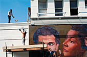 Workers by mural on wall, Los Angeles. California, USA