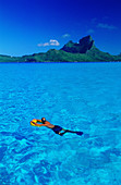 Lagoon with swimmer in lagoon at fore. Bora Bora. Leeward Islands. French Polynesia