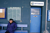 Retired fisherman sitting down at the harbour office entrance. Douarnenez. Finistere. Brittany. France