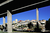 Working class housing suburbs seen through highway bridge piles. Lisbon. Portugal