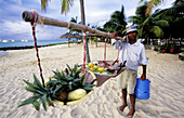 Man proposing fruits in baskets to the tourists. Paradise Beach. Morne Brabant. South West. Mauritius