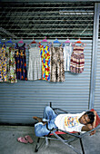 Clothes vendor asleep. Chatuchak Sunday Market. Bangkok. Thailand