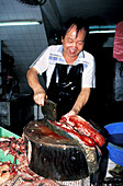 Fish and seafood shop with vendor cutting fish. Wanchai, Hong Kong. China