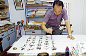 Chinese calligrapher at work in his studio. Macau, China