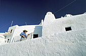 Woman outside her white walls home. Ia village. Santorini (Cyclades). Greece