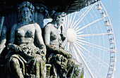 Statues of Place de la Concorde fountain and big wheel in background. Paris. France