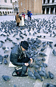 Man feeding the voracious pigeons. San Marco. Venice. Italy.