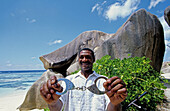 Plain clothes local policeman monitoring the beach and showing handcuffs. Anse Source d Argent beach and rocks. La Digue. Seychelles