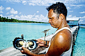 Black pearl grower opening on oyster from the lagoon. Takapoto atoll. Tuamotus archipelago. French Polynesia (MR)
