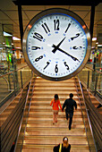 People and clock in the metro station of Plaça Catalunya, Barcelona. Catalonia, Spain