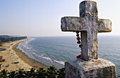 Cross and flowering offers with Arambol beach in background. Goa, India