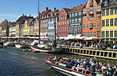 Tour boats, moored sailboat, ancient houses and waterfront cafe terraces at Nyhavn ( New Harbor ), Copenhagen. Denmark