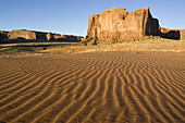 Structural forms in the sand against the background of a sandstone mesa in the southern part of the Monument Valley. Monument Valley Navajo Tribal Park, Navajo Nation, Arizona/Utah, USA.