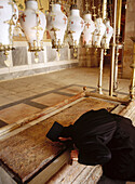 Monk kissing the Stone of the Anointing, believed to be the place where Jesus body was prepared for burial in the Church of the Holy Sepulchre, Jerusalem. Israel