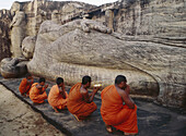 Monks offering flowers to Buddhan at dawn in Gal Vihara temple (built in the 12th century), Polonnaruwa. Sri Lanka