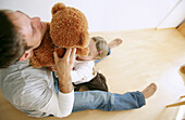 Vater und Tochter (3-4 Jahre) spielen mit einem Teddybär, München, Deutschland