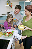Junge Familie bereitet Salat in der Küche zu, München, Deutschland
