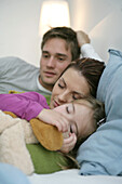 Young family lying on bed, mother and daughter sleeping, Munich, Germany