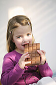 Girl (3-4 years) eating a bar of chocolate, Munich, Germany