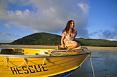 Frau sitzt am Bug eines Bootes, Rettungsboot, Resort Strand von Brampton Island, Whitsunday Islands, Great Barrier Reef, Australien