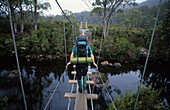 Wanderer läuft über den Hängebrücke über den Narcissus River, Cradle Mountain Lake St. Clair National Park, Tasmanien, Australien