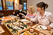 Drei Frauen essen Sushi an Bord einer Yacht, Shetland Inseln, Schottland, Großbritannien