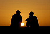 Two men sat talking in the desert at sunset, Offroad 4x4 Sahara Desert Tour, Bebel Tembain area, Sahara, Tunisia, Africa, mr