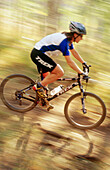 Mountain biker riding fast in forest at Deer Valley. Utah, USA