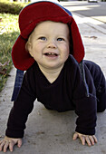 baby in hat crawling outside