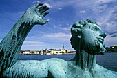 Statue of man dancing in celebration of life by Carl Eldh in the Stockholm City Hall (Stadhuset) Garden; Gamla Stan in background. Stockholm, Sweden