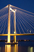 0501323 Kennewick-Pasco cable-stayed WA 397 Columbia R bridge reflected in river, fr Clover Island, illuminated at dusk. Kennewick, WA.