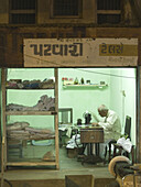 Tailor at work at night in his shop in Naroda, Gujarat, India