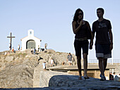 Tourists visiting a Christian shrine in the sun drenched harbour of Colliores, France on the Mediterranean coast.