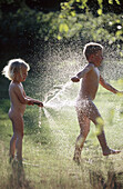 Two children, 3 and 6 years old, playing with water, in direct light. Medle. Vasterbotten. Sweden.