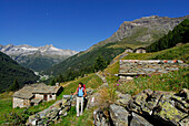 young woman hiking at alpine huts of Alp Senevedo, Bernina range, Italy