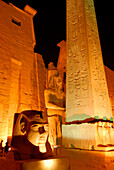 Kopf einer Ramses-Statue und Obelisk vor dem ersten Pylon im Luxor Tempel, beleuchtet in der Dämmerung, Ägypten, Afrika