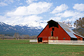 Red barn under the snow-covered Wallowa Mountains. Halfway. Oregon. USA